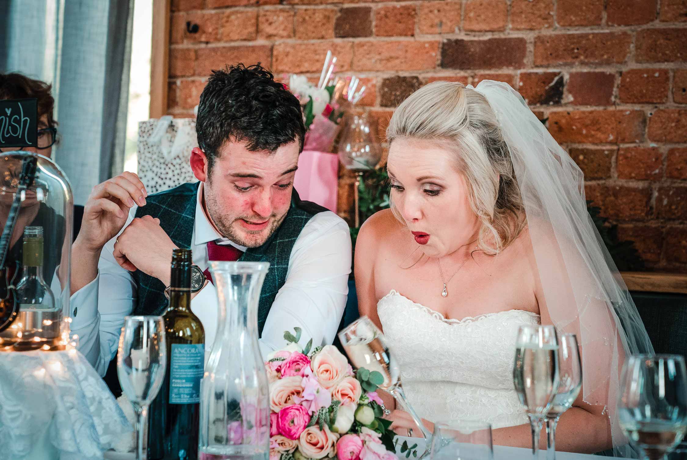 shocked look on bride & groom's face as she knocks over a glass of wine
