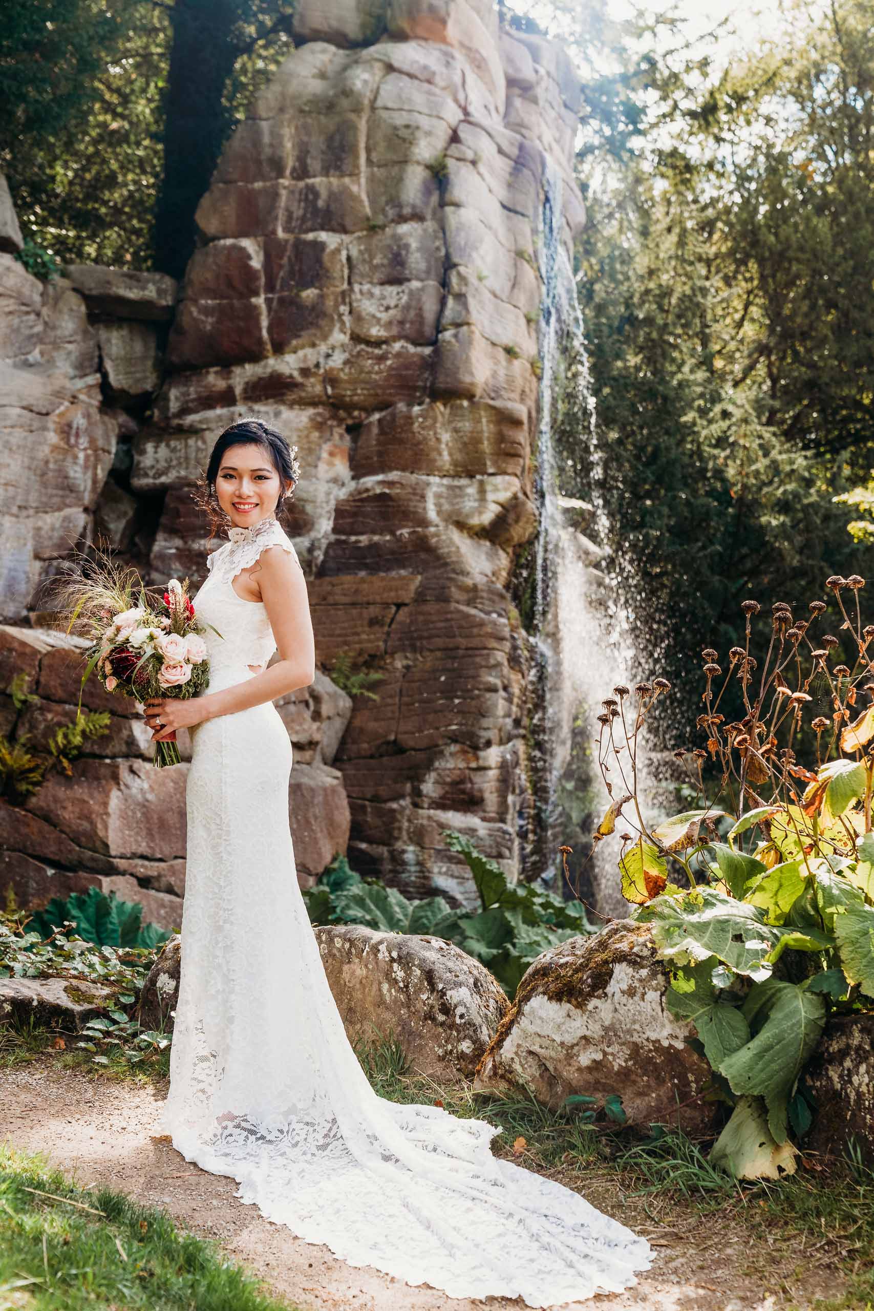 Beautiful Bride stood at waterfall near Chatsworth House gardens