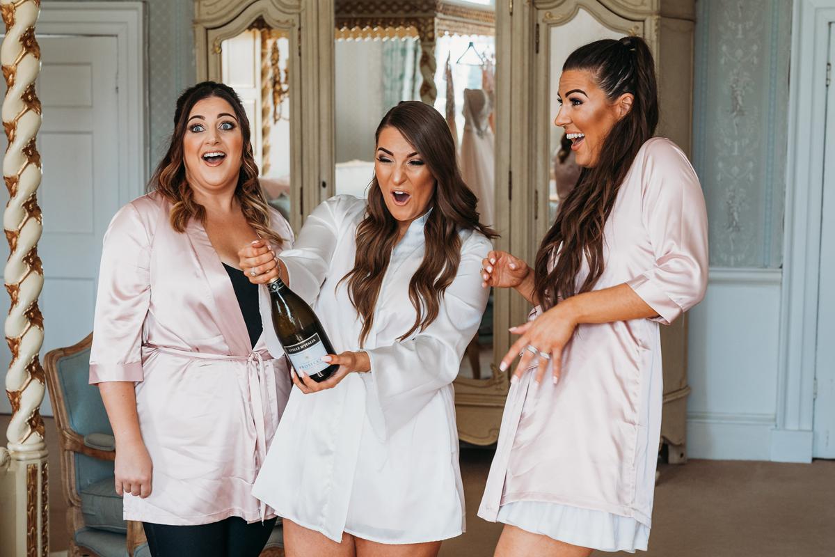 Norwood Park Wedding Photos of a bride surprised as she pops prosecco bottle with her bridesmaids