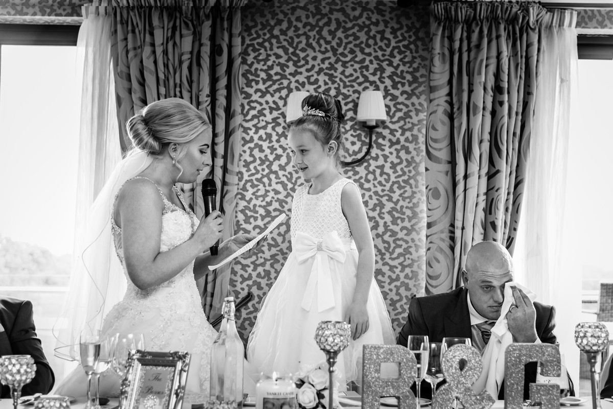 Bride gives a wedding speech whilst groom wipes away a tear