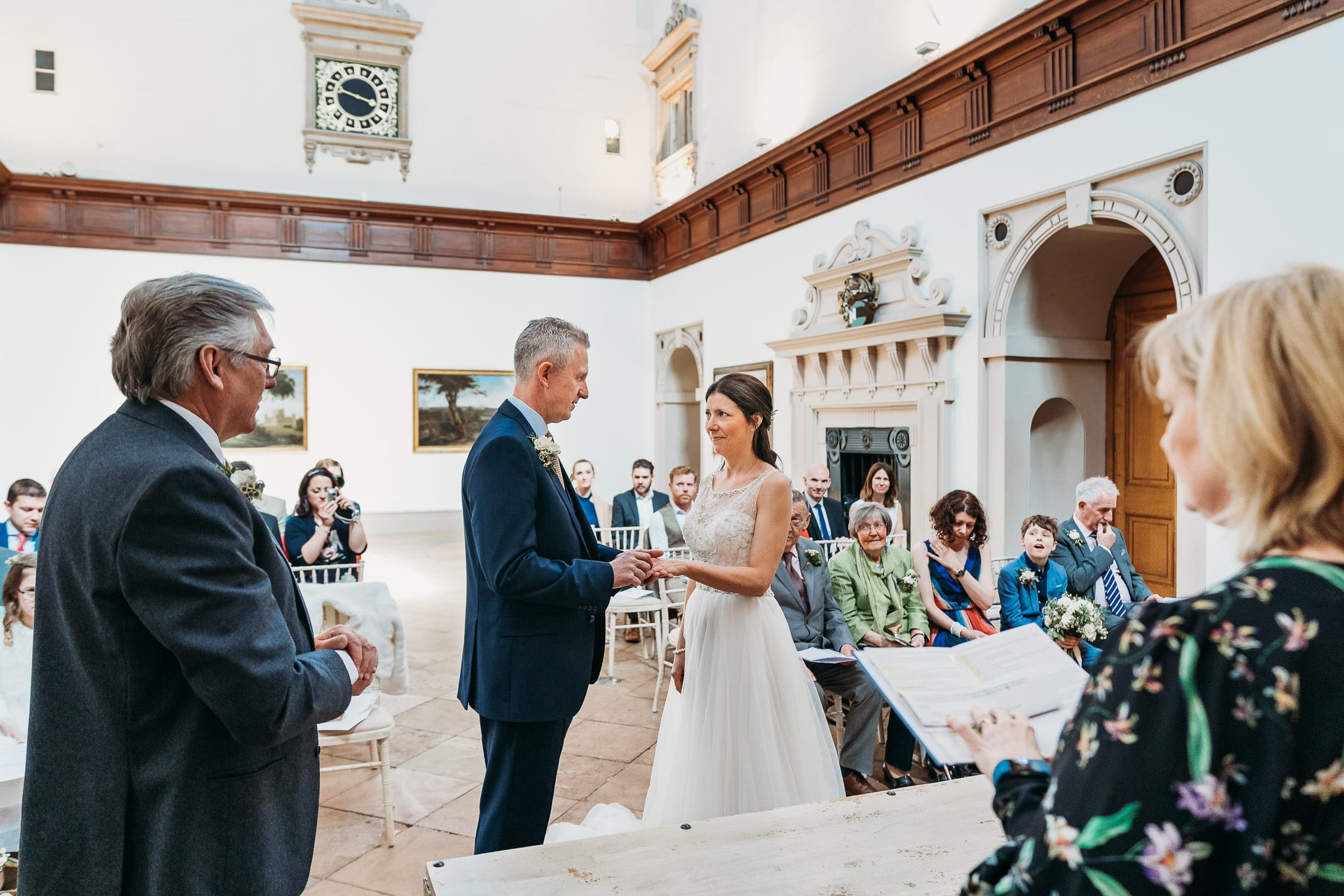 A photo of Bride and groom exchanging wedding rings during their wedding ceremony in the grand hall at Wollaton Hall Nottingham