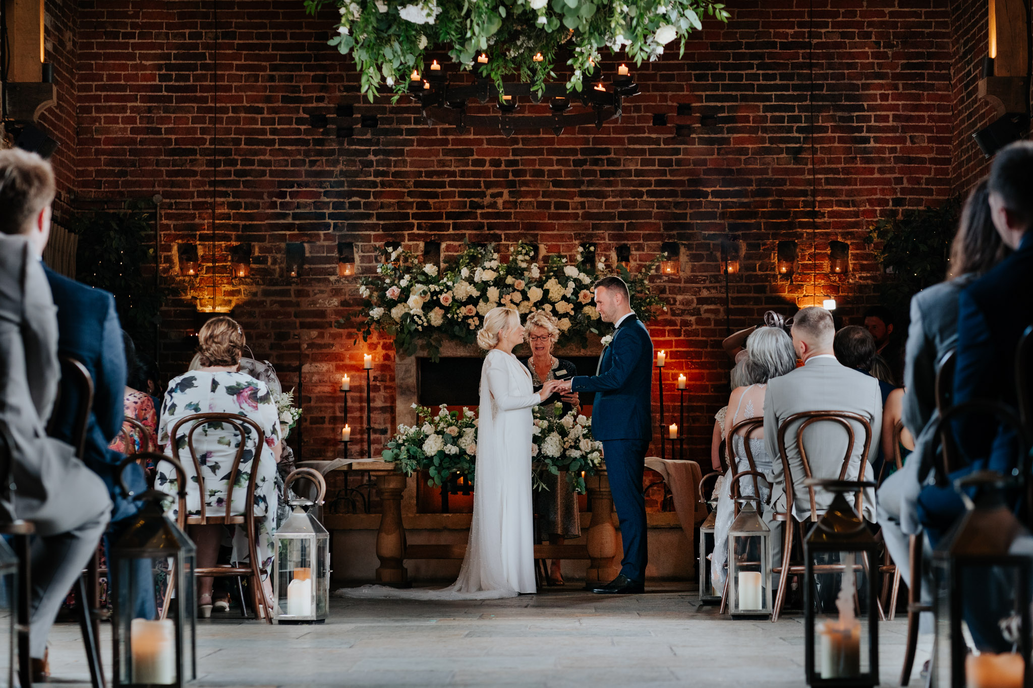 Wedding ceremony at Hazel Gap Barn. Bride & Groom exchanging rings at the front of the barn whilst guests look on